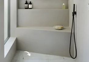 A minimalist walk-in shower with a sleek linear drain integrated into the tile floor, showcasing high-quality solutions from a professional floor drains manufacturer.