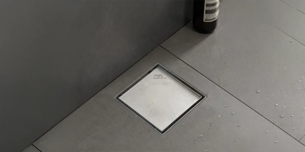 Industrial Floor Drains UAE featuring a square stainless steel drain installed in a tiled floor.