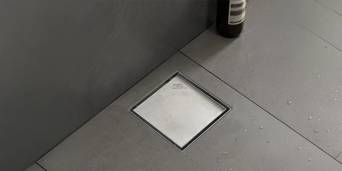 Industrial Floor Drains UAE featuring a square stainless steel drain installed in a tiled floor.