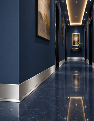 Elegant modern hallway featuring navy blue marble walls and glossy marble flooring, complemented by brushed stainless steel skirting, black door frames, warm recessed ceiling lighting, and contemporary wall art.