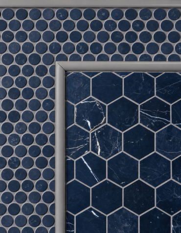 Close-up of navy blue circular mosaic tiles arranged in a grid beside a geometric hexagonal navy marble tile panel with light grey grout and a PVC profile border.